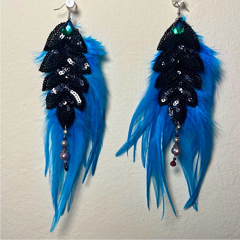 Black sequin earrings with bright turquoise feathers and silver accents.